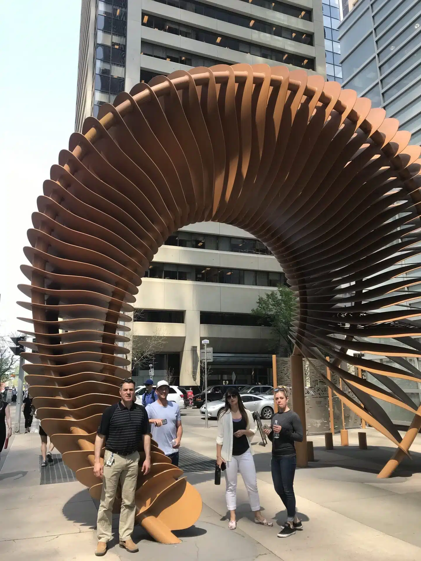 Scavenger hunt participants pose with a curved sculpture in Calgary