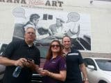 Photo of 3 people in front of a large mural