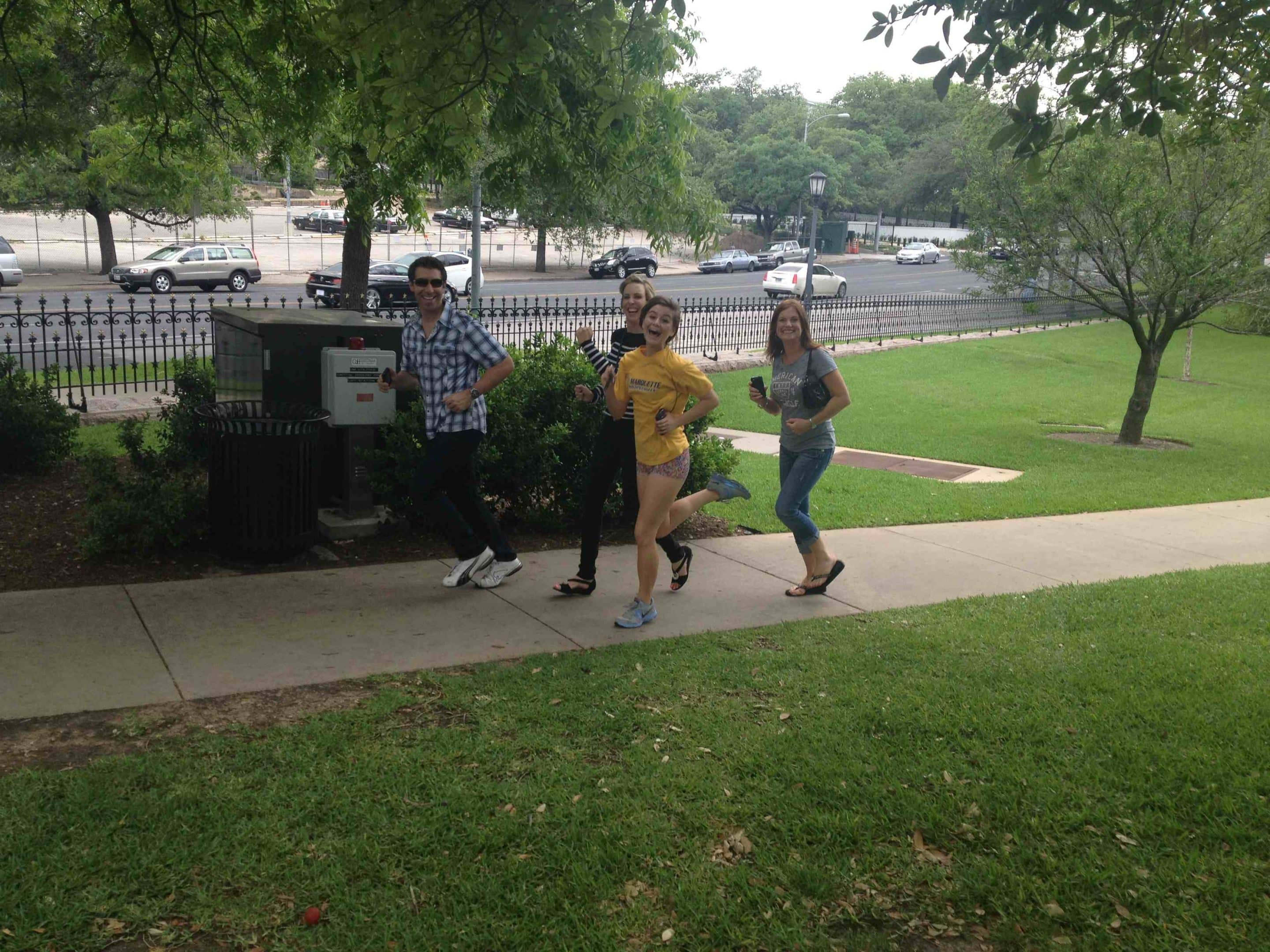 Four people jogging on an Austin sidewalk.