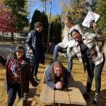 5 people in some sort of pose on a picnic table in the fall