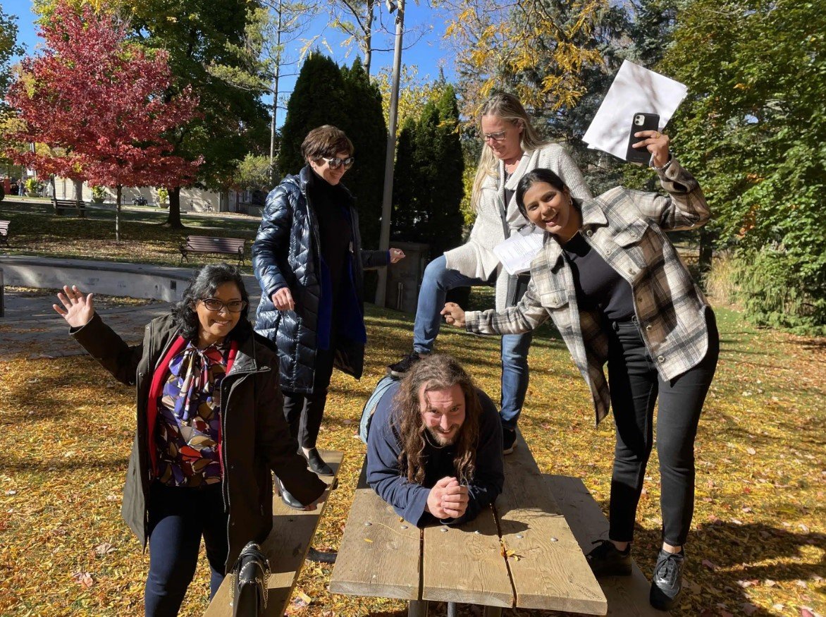 5 people in some sort of pose on a picnic table in the fall
