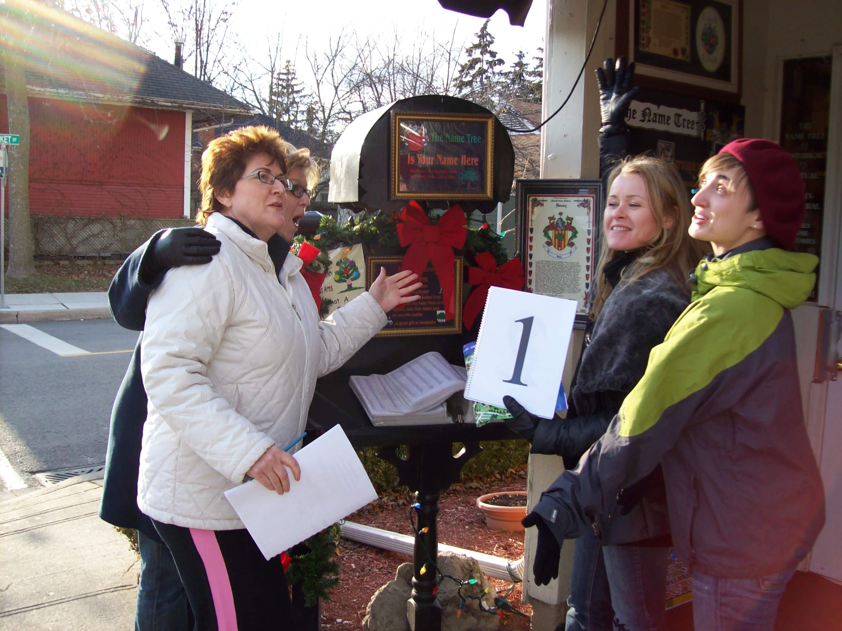 4 people sing with christmas decos in the background