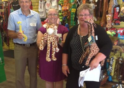 3 team members inside a shop, each holding a plushie during a team building activity in Kingston.