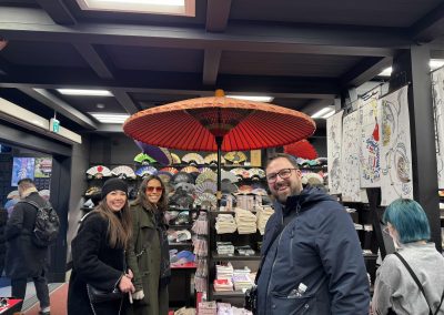 3 team members standing under a giant umbrella during a team building activity in Kyoto.