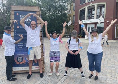 A scavenger hunt team of 5 making alphabet with their hands while standing.