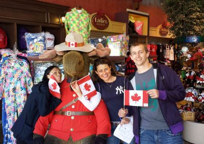 Team members taking a photo with a giant moose and holding a Canadian flag during a team building activity in Niagara Falls.