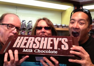 3 scavenger hunt team members about to bite a giant Hershey's milk chocolate during a team building activity in Niagara Falls.