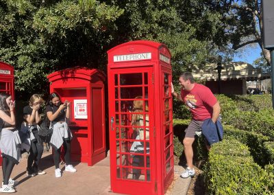 Scavenger hunt team member taking photo in a red telephone booth.
