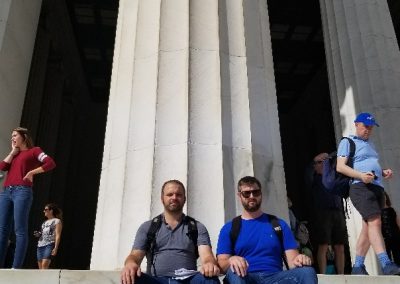 Two scavenger hunt team members sitting in front of a giant pillar.