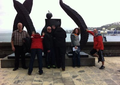 A team of 6 pressing against a giant structure during a team building activity in Wellington.