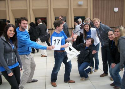 A scavenger hunt team of eight huddling together looking at the camera smiling.