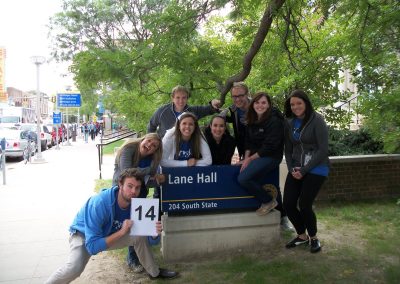 A group of eight people relaxing next to a retaining wall during the Ann Arbor Scavenger Hunt.