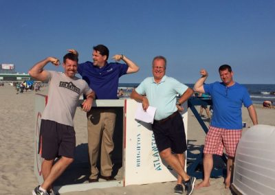 Scavenger hunt team members standing on a beach flexing their muscles.