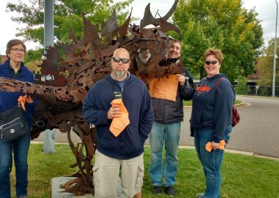 A scavenger hunt team of 4 members standing next to a sculpture shaped like a fish.