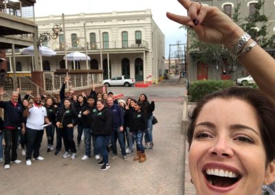 A woman takes a selfie with her team behind her during a team building activity in Galveston.