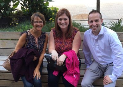 Three people sitting on a bench looking at the camera and smiling during a team building activity in Ithaca.