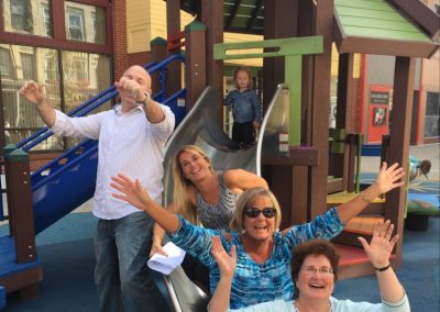 3 scavenger hunt team members sliding down a slide and another team member cheering them on