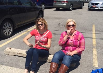 Two women sitting on a parking lot