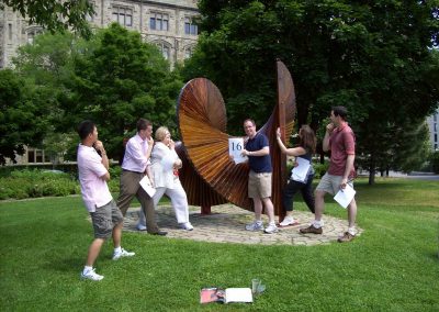 Six individuals are posing alongside a large spiral wooden structure during the Ottawa Scavenger Hunt.