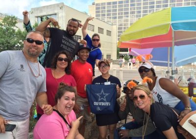 A team smiling and pointing at a flag looking at the camera during a team building activity in San Antonio.