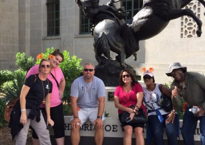 Scavenger hunt team of 6 members sitting in front of a Cowboy sculpture.