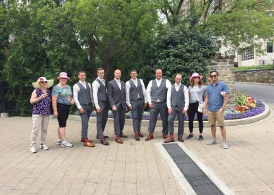 A team of four poses for a photo with a group of men, all standing together in a line