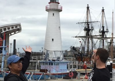 2 team members pointing at a beautiful lighthouse during a team building activity in Darling harbour.