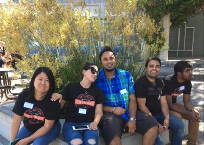 5 team members sit on a retaining wall during a team building activity in Los Altos.