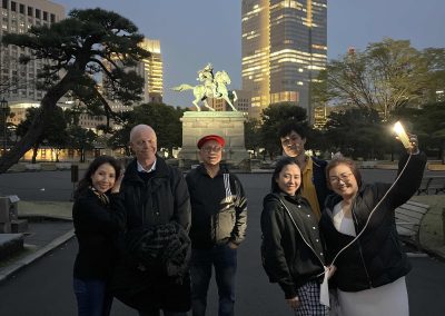 Scavenger hunt team takes a photo in front of a statue during a team building activity in Ginza, Tokyo.