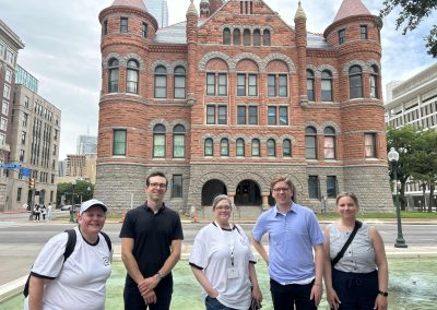 Teams standing in front of a beautiful ornate building during a team building activity in Dallas
