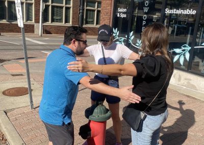 3 team members stand in circle over a water hydrant during a team building activity in Kansas City River Market