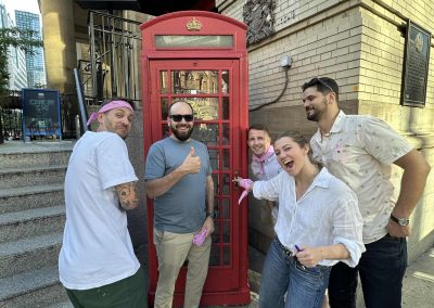 A scavenger hunt team takes photo in front of a telephone booth